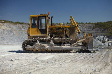 Obraz premium Crawler-mounted bulldozer in a quarry for limestone mining on a sunny day, close-up.