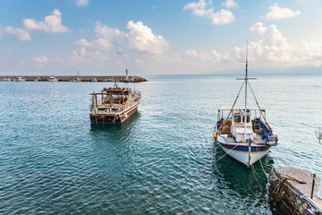 Obraz premium view of small fishing boats parked in a quiet bay of the Greek city of Hersonissos against a blue sky