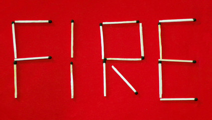 Inscription fire from matches. The word fire is laid out from matches on a red background. Concept of fires and arson. Creative and original.