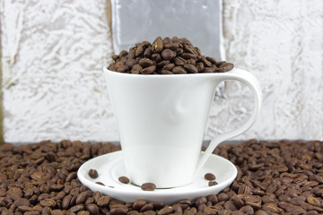 Dark roasted coffee beans in a cup and saucer