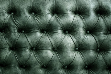 Close-up of an elegant Chesterfield pattern green leather sofa.