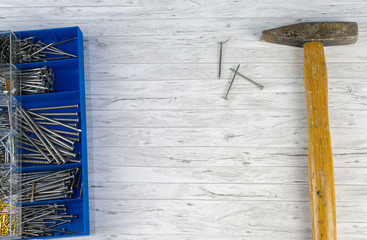 Hammer and a blue box with nails on white wood background, copy space