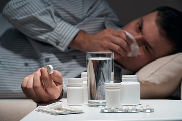 Overworked businessman is lying on the sofa and resting. Pills and glass of water near him.