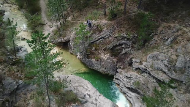 Aerial man film himself in alpine landscape nea a turquoise waterfall