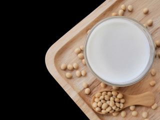 Fototapeta na wymiar soy milk and soybean on the wood tray on black background