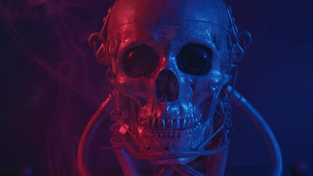 Robotic skull in red and blue light with smoke