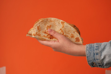 Mexican national food taco or Tatar national food kystyby in hand on an orange background.Food in a tortilla.National food concept