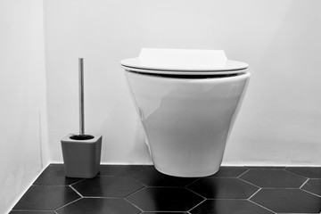 Suspended toilet in wc with black tiles on the floor