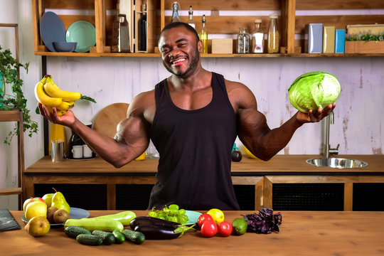 Strong black man chooses vegetables and fruits in the kitchen. Dietary food for the athlete.