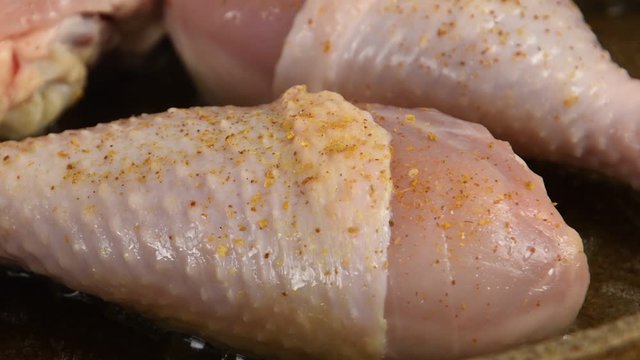 Sprinkle spices on chicken legs in a pan closeup