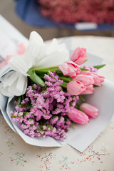 Bouquet with pink tulips and small pink flowers in a white wrapping paper