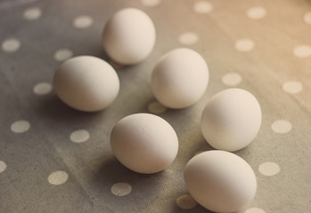 White chicken eggs, shot from above on a background of gray fabric with white polka dots, use: Easter decoration, kitchen