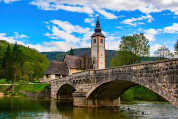 Fototapeta na wymiar Scenic view of stone bridge and church of St John the Baptist on Bohinj Lake, Slovenia