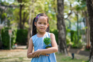 little girl hugging small artificial plant in a garden