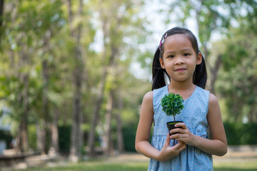 portrait of a girl in park. hand holding small artificial plant.