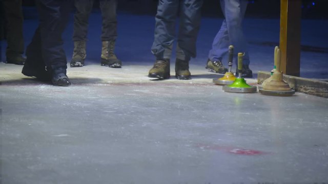 People throwing curling stone on the ice.