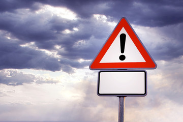 triangle road sign with exclamation point  and cloudy sky