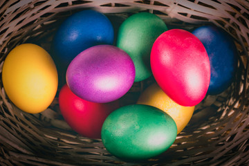 Close-up of multicolored traditional easter eggs painted in blue, pink, purple, yellow colors in basket. Vintage tone. Macrophotography. Vibrant easter festive background.