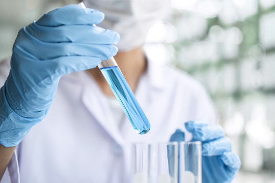 Scientist Or Medical In Lab Coat Holding Test Tube With Reagent, Laboratory Glassware Containing Chemical Liquid, Microscope, Biochemistry Laboratory Research