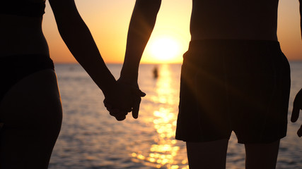 Couple holding hands each other and walking at sunset