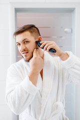 Man shaves his beard with an electric razor