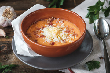 Healthy vegan pumpkin soup on wooden table with ingredients around