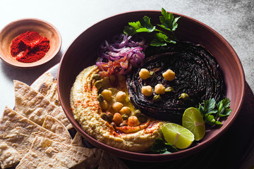 Fototapeta na wymiar a bowl of hummus, baked purple cabbage and pickled red onion with a tortilla and smoked paprika