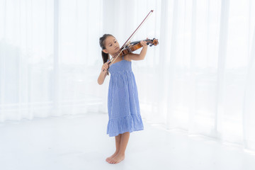 Asian Girl are playing violin in the white room. © KanyaphatStudio