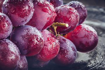 Makrofotografie von frischen, dunkelroten  Weintrauben mit Wasserspritzern auf dunklem Hintergrund