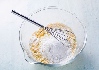 mixing dry ingredients in a glass bowl with a whisk