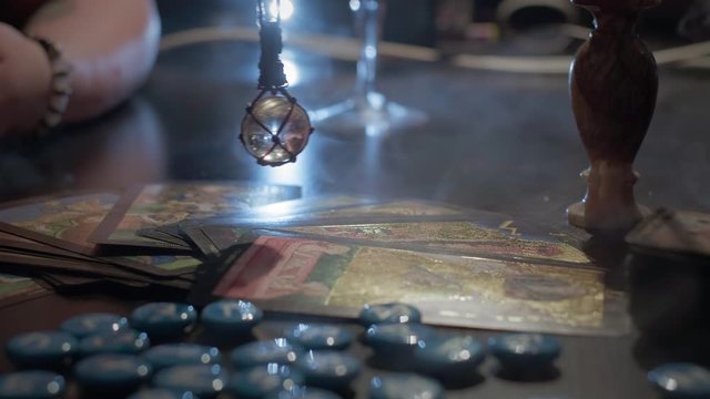 The sorceress holds in her hands a crystal ball. Conducts a spiritualistic session. Engaged in black magic, associated with the spirits and souls of the dead. Otherworldly forces, anamalous activity.
