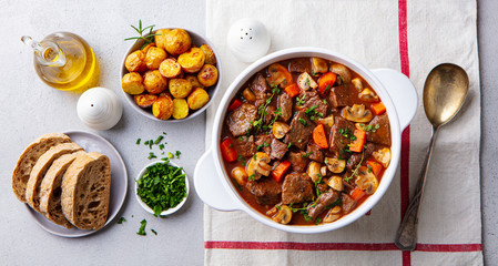 Beef bourguignon stew with vegetables. Grey background. Top view. - obrazy, fototapety, plakaty