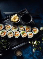 vegan sushi with tofu in General Tso sauce, avocado and fresh vegetables . on a table with branches of a blossoming tree