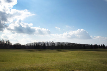 Golf course against the sky with white clouds in early spring
