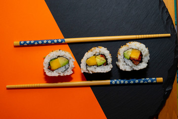 Pieces of vegetarian sushi on an orange background.