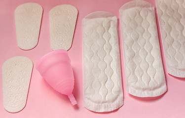 Sanitary pad, menstrual cup on pink background
