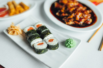 White plate with traditional sushi, asian food on table
