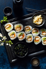 vegan sushi with tofu in General Tso sauce, avocado and fresh vegetables . on a table with branches of a blossoming tree