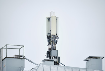 Cellular phone network telecommunication tower on the building roof.