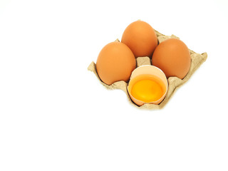 A group of eggs and fresh half-cracked egg in brow paper tray isolated on white 