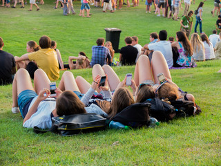 Bremen, Germany, 23 July, 2014: Four girls laying on the grass on the festival starring on their smartphones.