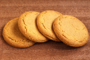 A row of four ginger biscuits on a dark wooden background