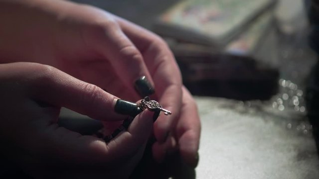the witch holds a magic bracelet in her hands. Sorting rosary in hands.