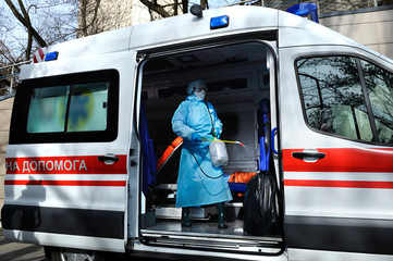 Paramedics disinfecting the ambulance car with the motorized backpack atomizer and sprayer