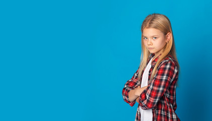 Kids violence. Offended teen boy standing with folded arms, grey panorama background with empty...