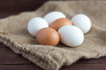 White and brown chicken eggs on a dark wooden background.