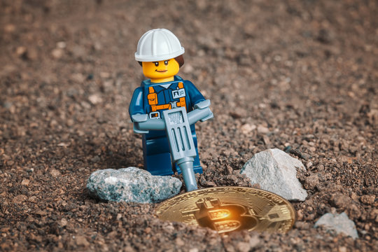 ANKARA, TURKEY. NOVEMBER 17, 2019. Lego mini woman miner figurine working with pneumatic hammer and breaking rocks to uncover glowing bitcoin. Cryptocurrency and mining concept.