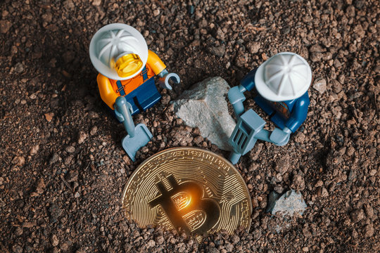 ANKARA, TURKEY. NOVEMBER 17, 2019. Lego mini miner figurines working with tools on ground to uncover glowing bitcoin. Cryptocurrency, blockchain and mining concept.