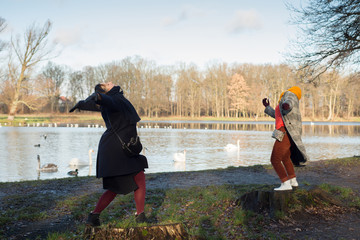 Two women dancing in a park by the lake with swans