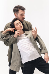Supporting. Trendy fashionable couple isolated on white studio background. Caucasian woman and man posing in basic minimal stylish clothes. Concept of relations, fashion, beauty, love. Copyspace.